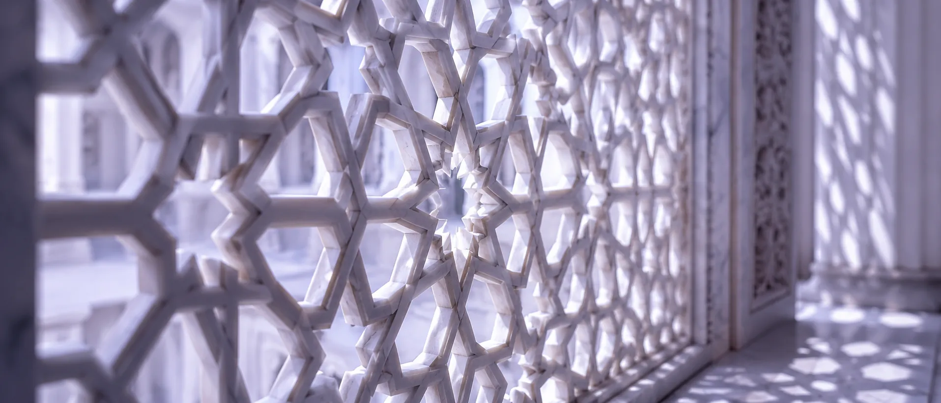 Light passing through an intricate white marble jali lattice screen
