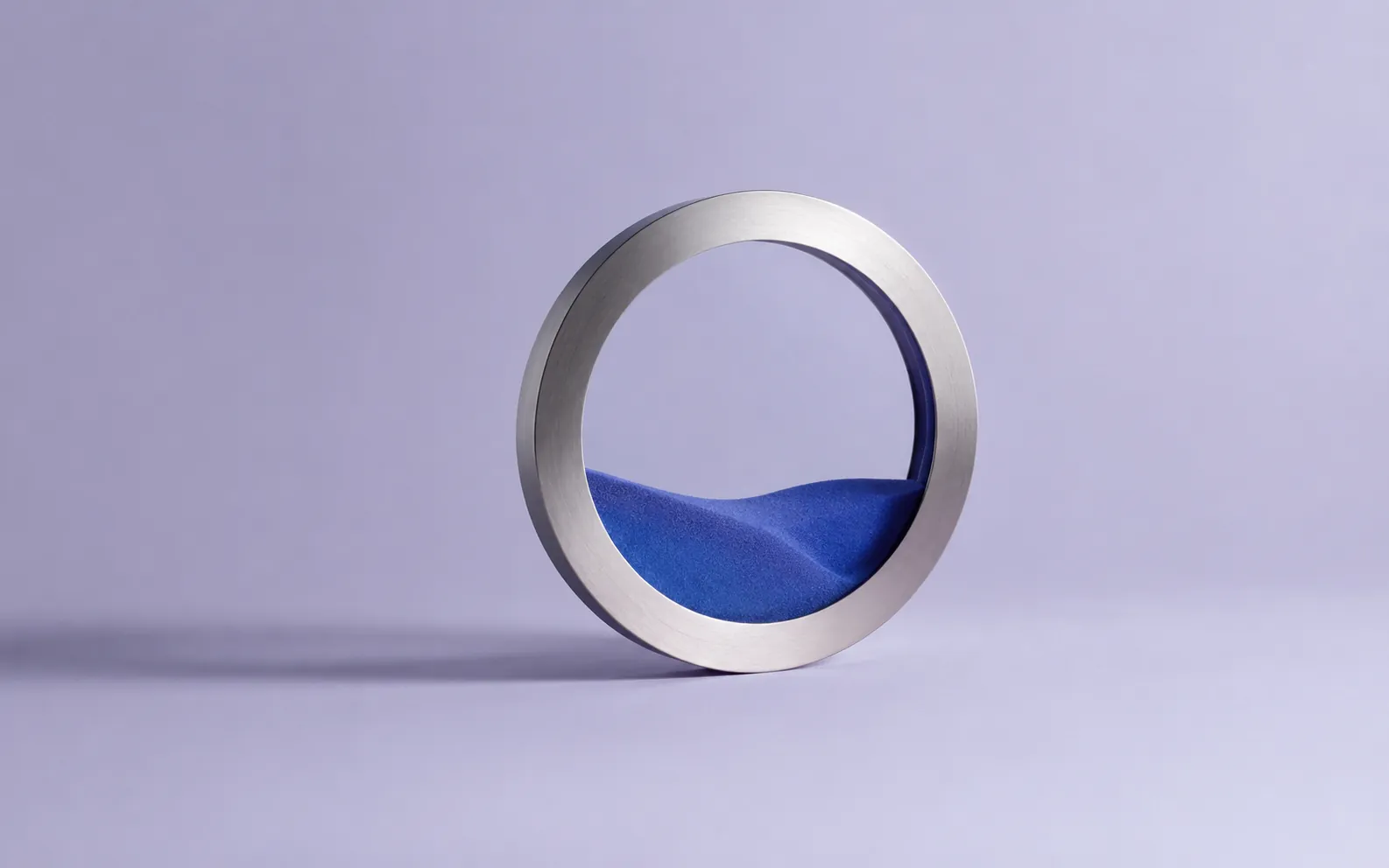 Blue sand settled calmly inside a brushed silver ring